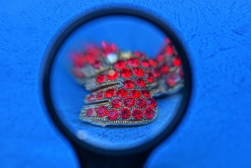 magnifier and old golden jewelery with small red rubies on the blue table