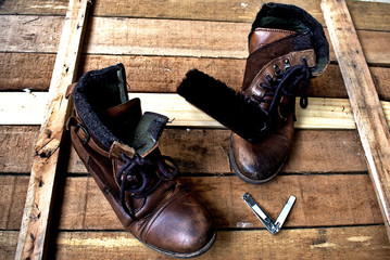 Brown leather boots and a show brush on a wooden floor