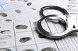 © New Africa - Handcuffs and fingerprint record sheets, closeup. Criminal investigation