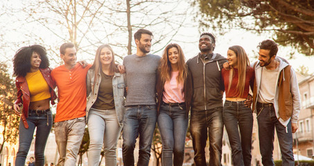 Wall Mural - Group of multiracial young people students arms around shoulders together in a park