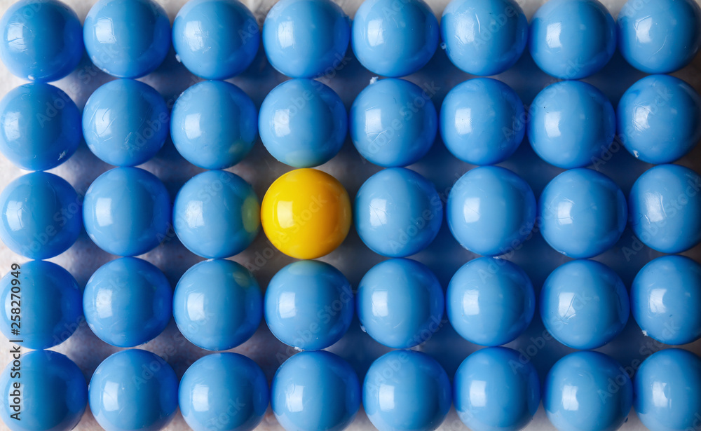 Yellow ball among blue ones, top view. Concept of uniqueness