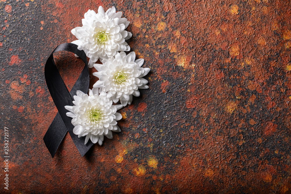 Black mourning ribbon and flowers on grunge background