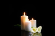 Burning candles and flowers on dark background