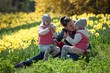 © Ji - cute twin sisters, embrace on a background field with yellow flowers, happy cute and beautiful sisters having fun with mother in yellow flowers in spring in park, cheerful holidays outdoors