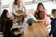 © InfiniteFlow - Businesswoman in group meeting discussion with other businesswomen colleagues in modern workplace office with laptop computer and documents on table. People corporate business working team concept.