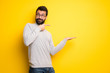 Man with beard and turtleneck holding copyspace imaginary on the palm to insert an ad