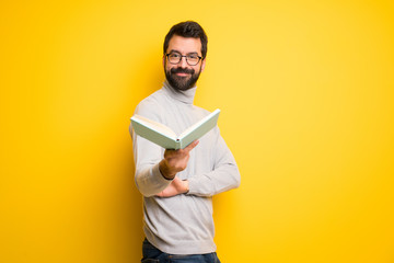 Wall Mural - Man with beard and turtleneck holding a book and giving it to someone