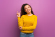 © luismolinero - Teenager girl over purple wall smiling and showing victory sign