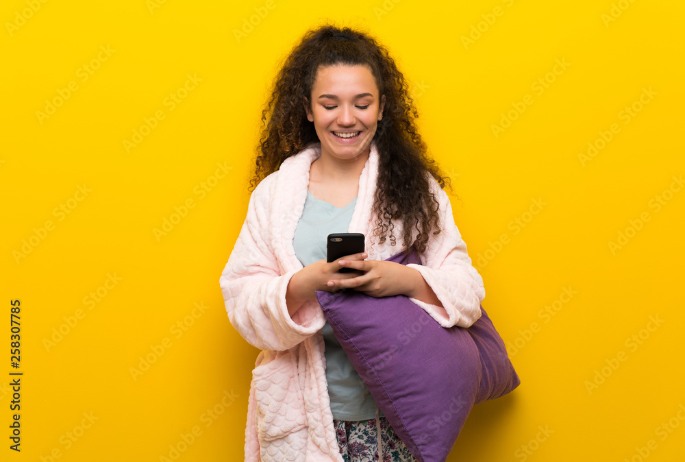Teenager girl in pajamas sending a message with the mobile - obrazy, fototapety, plakaty 