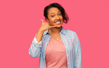 People Concept - Happy African American Young Woman Making Phone Calling Gesture Over Pink Background