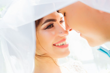 The bride with a beautiful makeup smiles to the groom. covered w