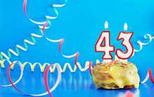 Birthday Of Forty Three Years. Cupcake With White Burning Candle In The Form Of Number 43. Vivid Blue Background With Copy Space