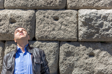 Man with leather jacket and blue shirt looks towards the sun