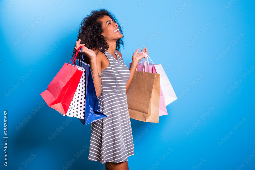 Young black woman holding shopping bags on blue backgrond. Stock Photo ...