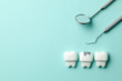 Healthy white teeth and tooth with caries on green mint background  and dentist tools mirror, hook. Copy space for text.