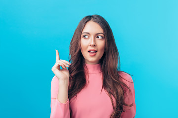 Wall Mural - Young beautiful woman having good idea with her finger pointing up isolated on blue background