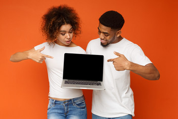 Young black couple pointing at blank laptop screen