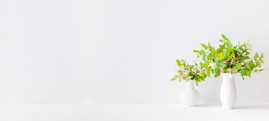 Home interior with decor elements. Branches with green leaves in a vase on a white table