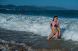 © Михаил Решетников - beautiful young woman in a seductive bikini comes out of the sea with high waves. Big waves in the ocean
