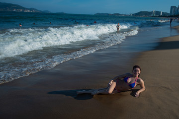 A young woman in a seductive bikini lying on the beach. Girl lying on the sand by the ocean