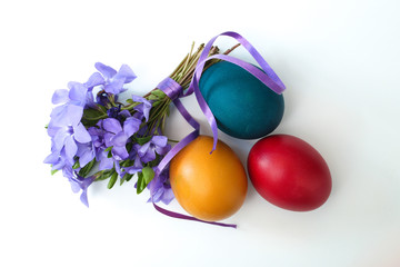 Top view of  periwinkle  flower Bouquet and three painted easter eggs