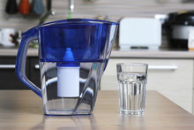 Glass Of Clean Water And Filter For Cleaning Drinking Water On The Table In The Kitchen. Purification Of Drinking Water At Home.