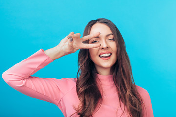 Wall Mural - Happy beautiful woman showing peace sign isolated on blue background