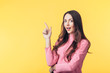 © GVS - Beautiful surprised woman showing empty copy space pointing her fingers isolated on yellow background