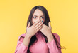 © GVS - Surprised excited woman covering her mouth with hands on yellow background
