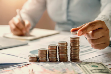 business woman hand holding coins to stack on desk concept saving money finance and accounting