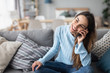 © BestForYou - Smiling woman talking on the phone at home on the sofa.
