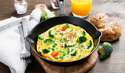 Wall Mural - Baked omelette with green vegetables- broccoli, sweet pea and tomato in a skillet .