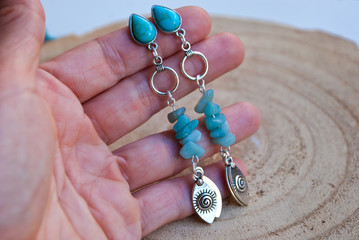 Handmade silver turquoise long boho earrings in woman hand. Trend luxury jewelry.