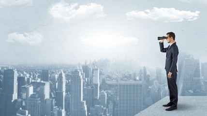 Wall Mural - businessman looking forward to a city with binoculars from skyscraper concept
