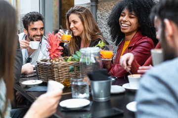 Group of multiracial friends having fun time in a coffee drinking coffee cappuccino and fruit juice