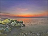 Fototapeta Morze - Ocean water rushing by a rock on twilight time.
