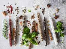 Various Spices In Glass Test Tubes And Fresh Herbs On Gray Background. Set Of Various Spices And Herbs Flat Lay