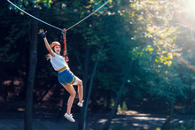 Happy Women Girl Female Gliding Climbing In Extreme Road Trolley Zipline In Forest On Carabiner Safety Link On Tree To Tree Top Rope Adventure Park. Family Weekend Children Kids Activities Concept