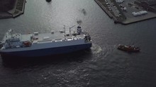 Aerial Of Tugboat Towing Ship Entering Harbor Docks