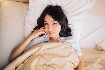 Wall Mural - Portrait pretty young girl on bed in modern apartment in the morning