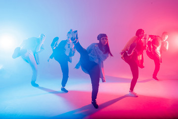 Group of diverse young hip-hop dancers in studio with special lighting effects in blue and pink colores