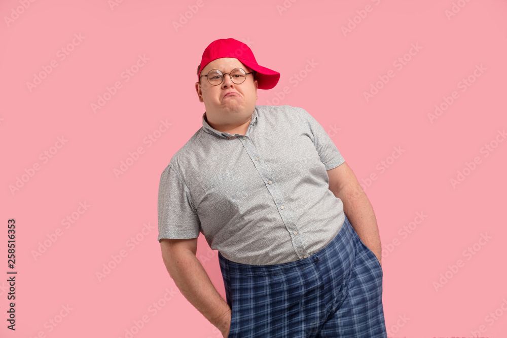 Comical home superhero with arrogant face wearing checkered huge shorts shows his muscles and competence isolated on pink background - obrazy, fototapety, plakaty 