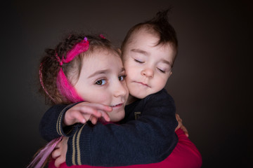 Boy and girl hugs together and smile. Brother and sister in studio