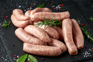 Wall Mural - Freshly made raw butchers sausages in skins with herbs on stone board