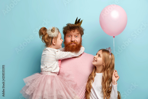 Photographie Busy father organizes holiday on International childrens day for two daughters, have home party, wear crowns and festive clothes