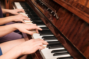 Wall Mural - Brother and sister play at four hands on the piano at home and study a new musical piece