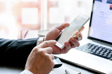 Wall Mural - cropped view of businessman hand using mobile smartphone while sitting at office desk.