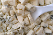 Close view of crumbled blue cheese with a spoon in the food