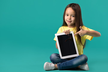 cute little child girl holding blank tablet computer on blue background