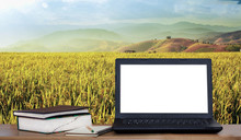 Laptop And Books On Desk With Rice Field And Mountain Background